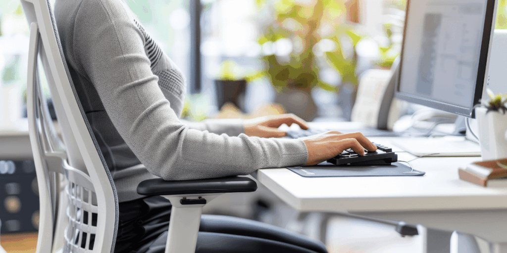 Berufstätige Person macht Stretching-Pause am Schreibtisch im Homeoffice